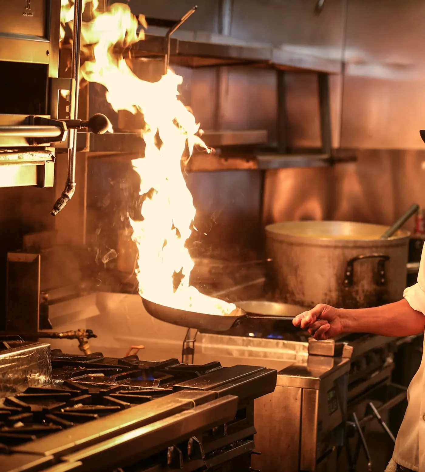 A pan flaring over the hearth in a dark kitchen