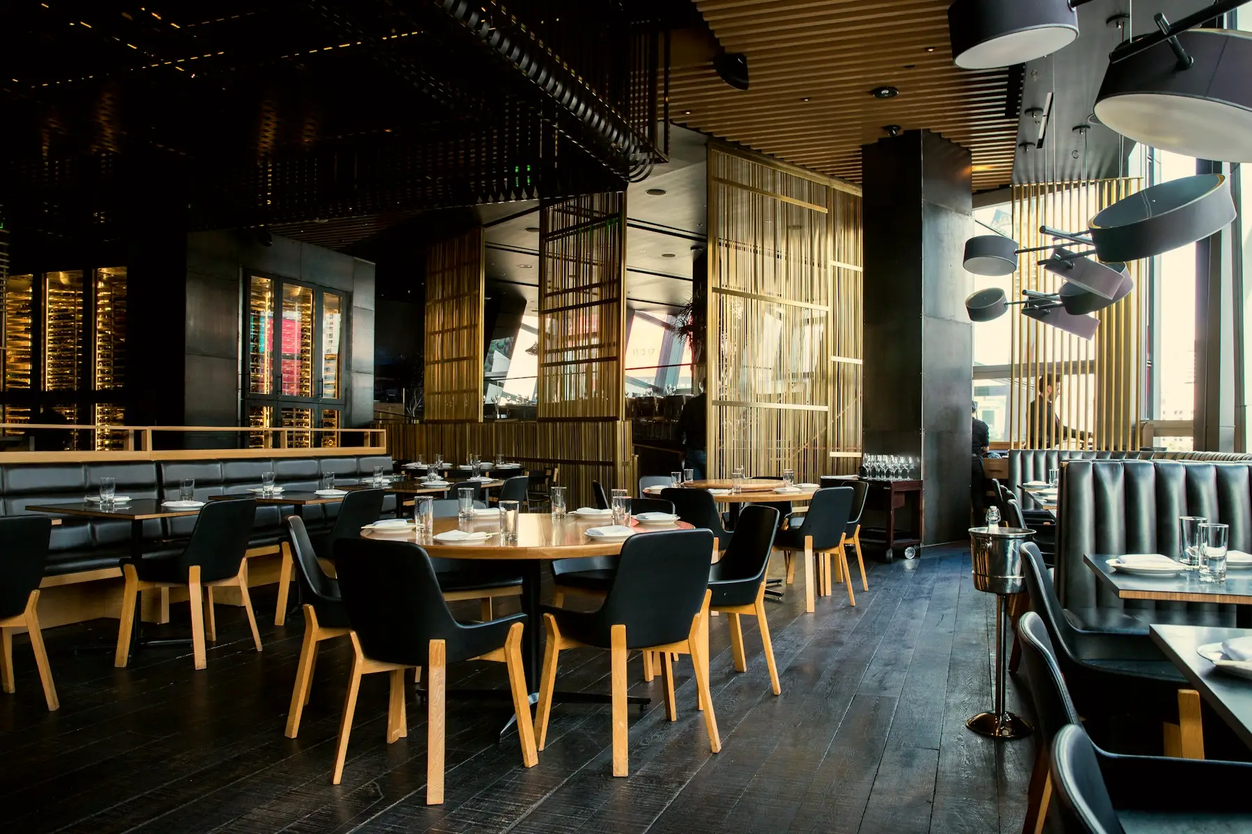 The dining room in low light with banquettes and pendant lamps