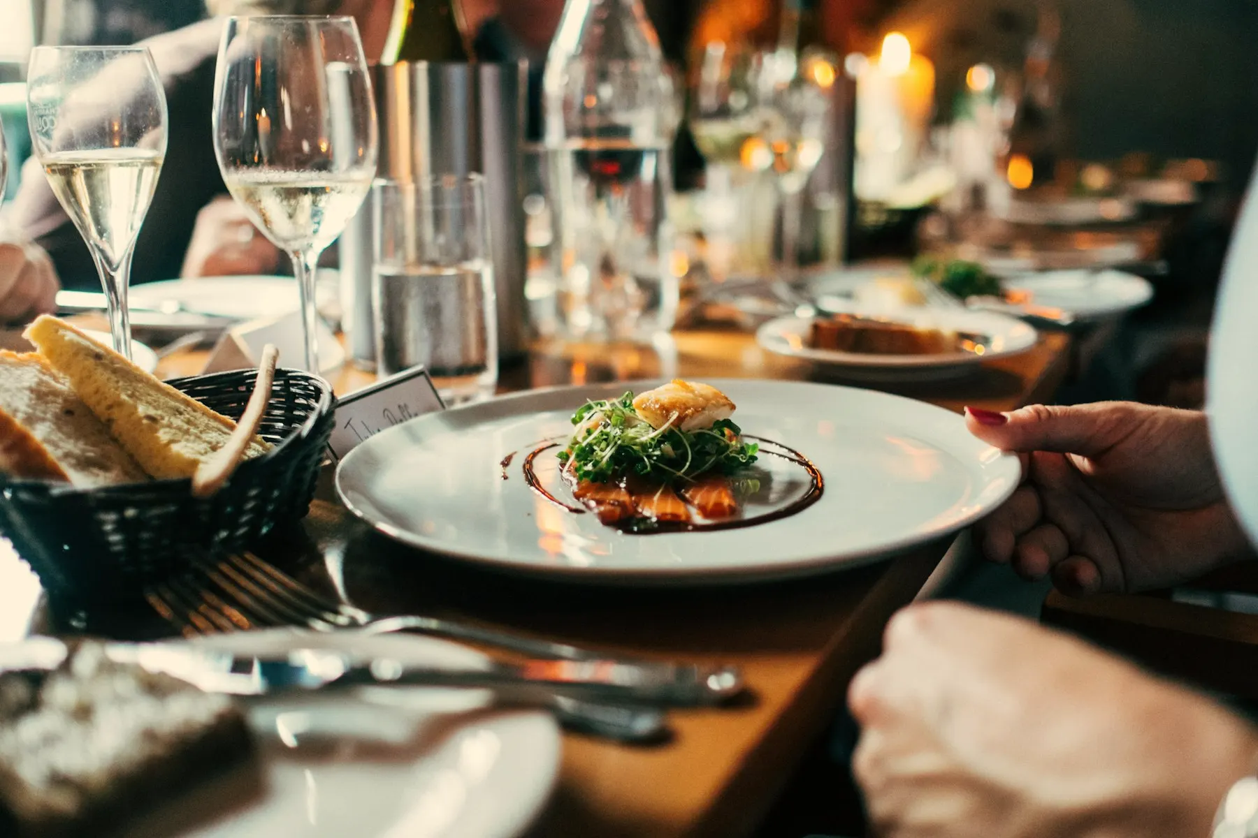 A plated course on a set table with white wine